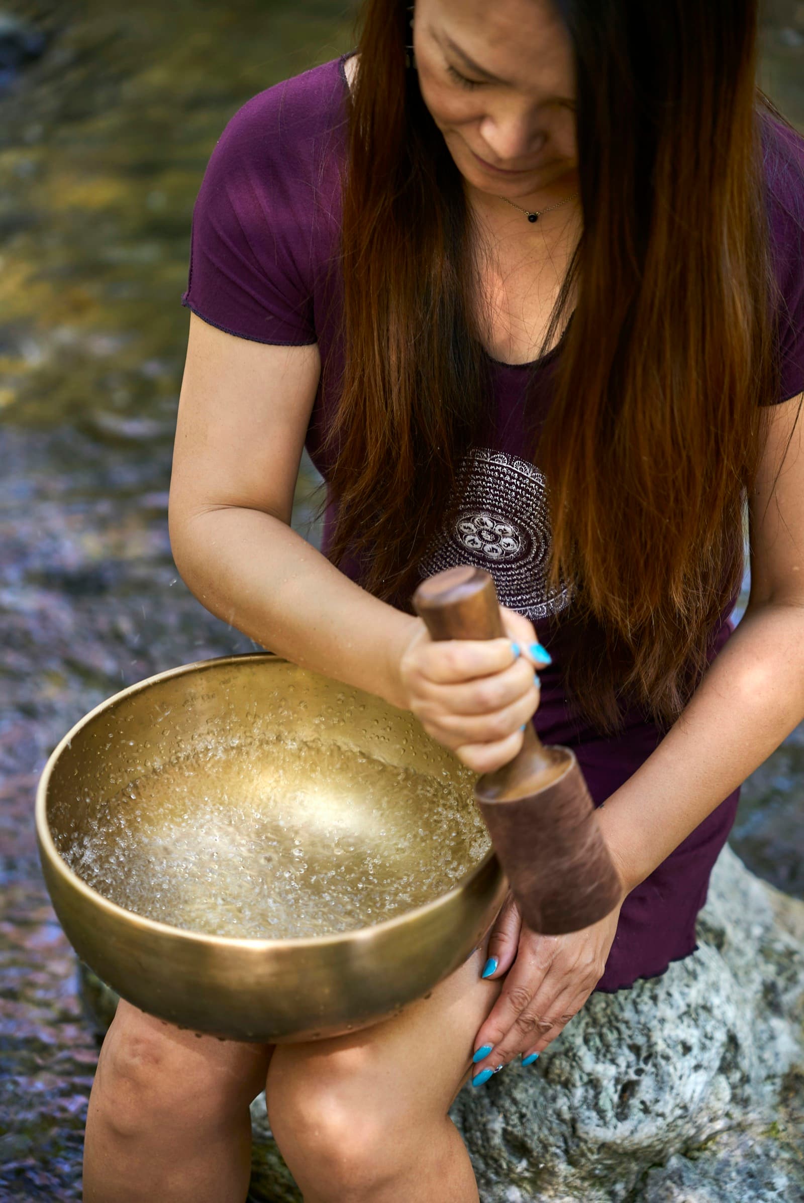 Hands striking a large bronze singing bowl